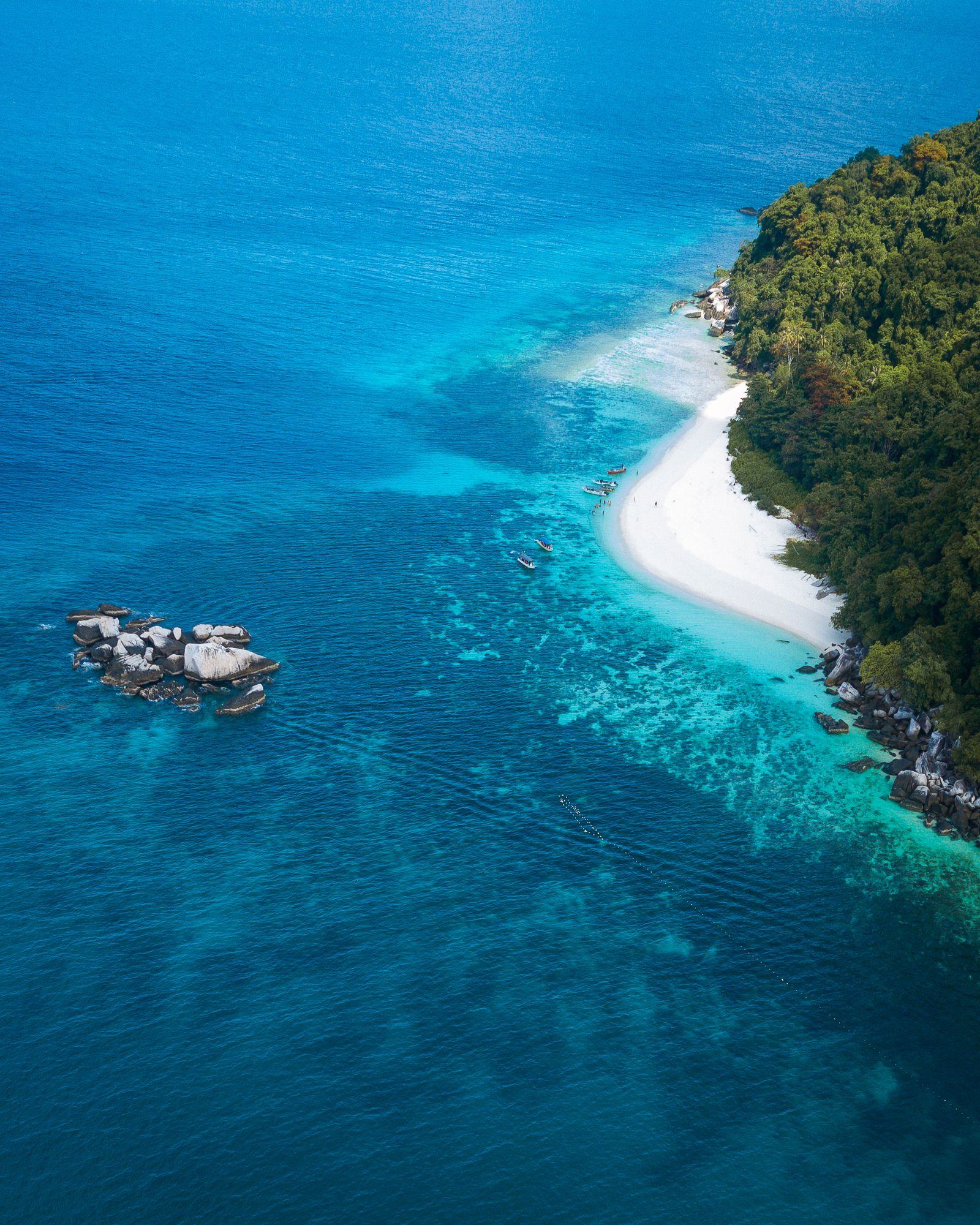 A boat anchored in clear turquoise water off Tioman Island